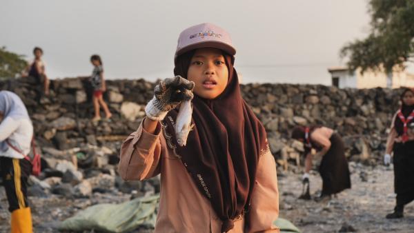 Nina hält einen toten Fisch in der Hand, den sie bei einer Müllsammelaktion mit ihrer Pfadfindergruppe gefunden hat. | Rechte: SWR/Sonam Rinzin
