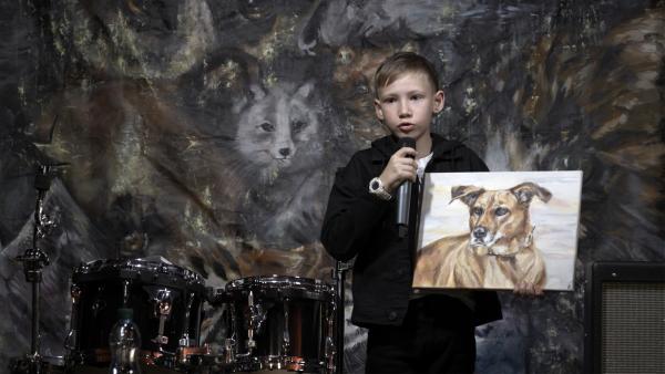 Pavel auf der Bühne des Tierrechte-Rock-Festivals bei der Versteigerung seines Gemäldes für wohltätige „Tier-Zwecke“