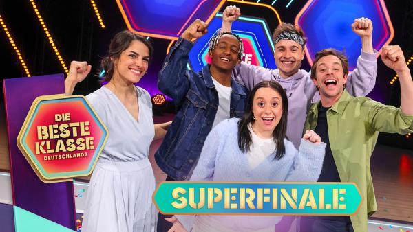 Clarissa, Bac, Maria Ziffy, Fabian Baggeler und Tobi stehen zusammen mit erhobenen Armen im Studio von "Die beste Klasse Deutschlands". Ihre Hände sind zur Faust geballt. Alle sind voller Vorfreude auf das Superfinale.